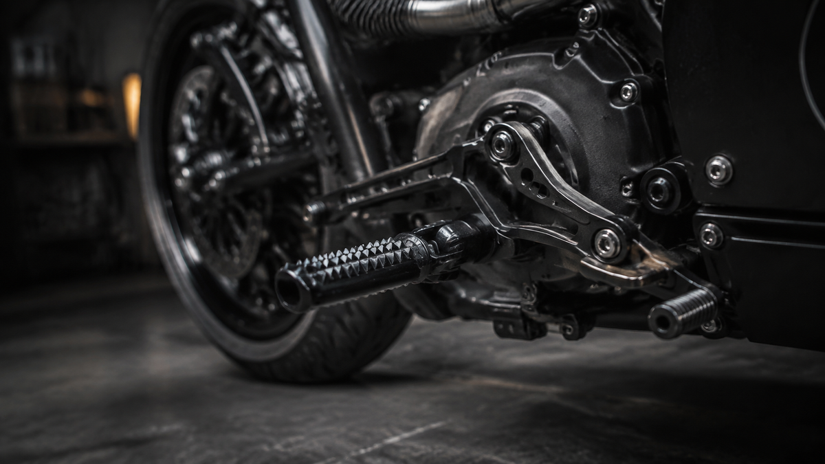 Schwarze griffige Fußrasten und Schaltanlage eines Custom Motorrads