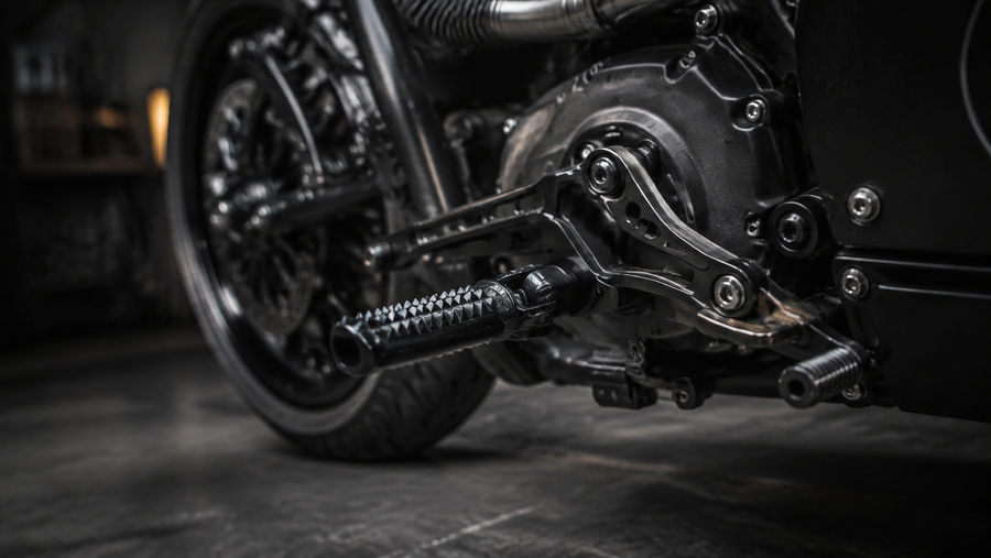 Schwarze griffige Fußrasten und Schaltanlage eines Custom Motorrads